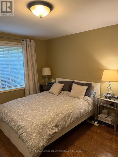 A bedroom with a bed, nightstand, and window.