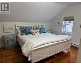 A bedroom with a bed, nightstand, and window.