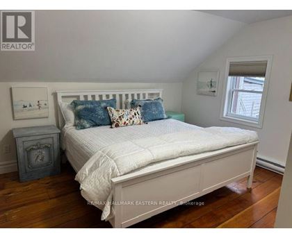 A bedroom with a bed, nightstand, and window.