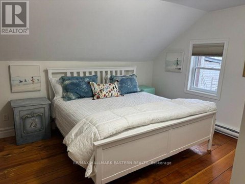 A bedroom with a bed, nightstand, and window.