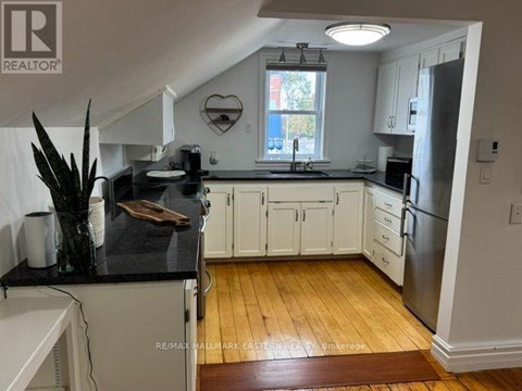 A kitchen with white cabinets and a black counter top.