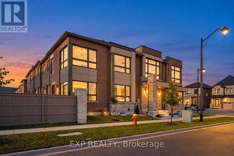A modern house with a well-lit front yard at dusk.