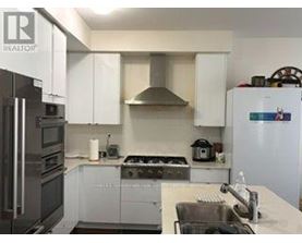 A kitchen with white cabinets and a stainless steel refrigerator.