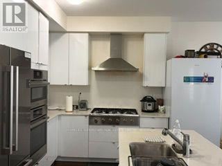 A kitchen with white cabinets and a stainless steel refrigerator.