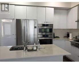 A kitchen with a white counter top and stainless steel appliances.