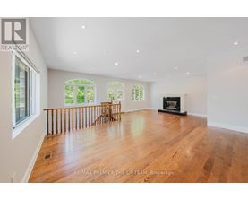 A spacious room with wooden floors and a fireplace.