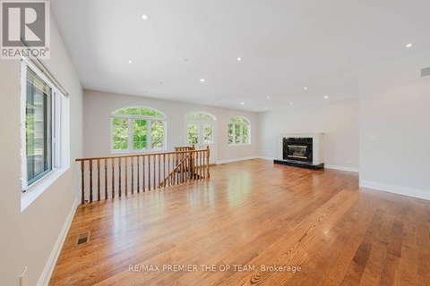 A spacious room with wooden floors and a fireplace.