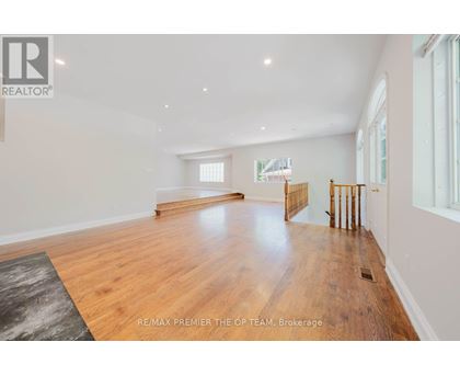 A spacious room with wooden flooring and white walls.