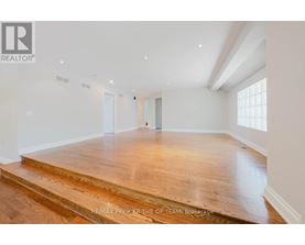 A spacious room with wooden flooring and white walls.