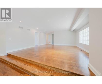A spacious room with wooden flooring and white walls.