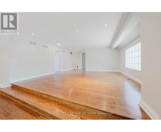 A spacious room with wooden flooring and white walls.
