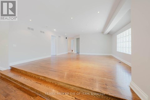 A spacious room with wooden flooring and white walls.