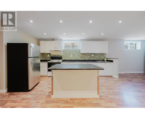 A kitchen with a black fridge and a stone backsplash.