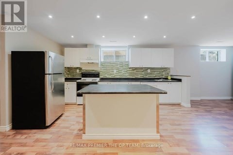 A kitchen with a black fridge and a stone backsplash.