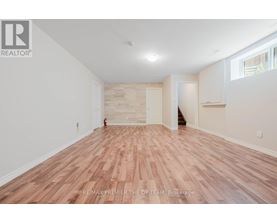 A room with wooden flooring and white walls, with a logo that reads RE/MAX PREMIER THE OP TEAM, Brokerage.