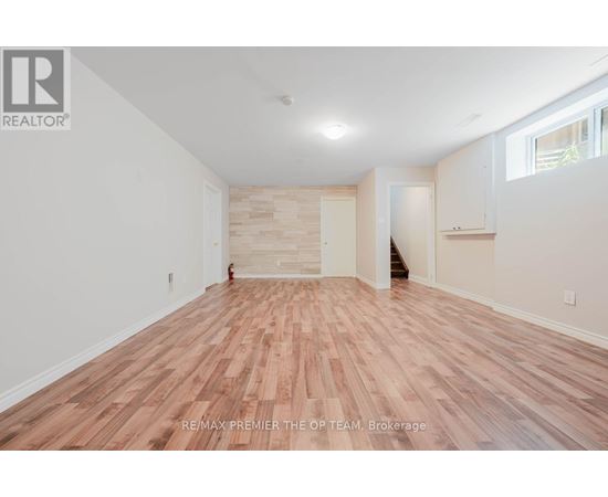 A room with wooden flooring and white walls, with a logo that reads RE/MAX PREMIER THE OP TEAM, Brokerage.
