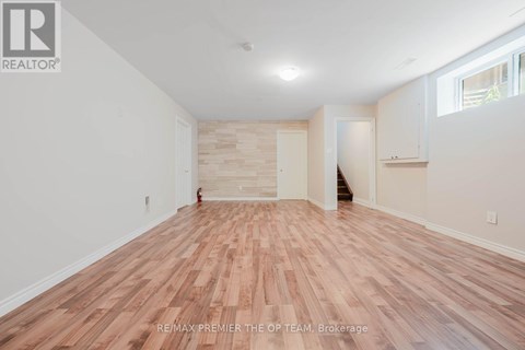 A room with wooden flooring and white walls, with a logo that reads RE/MAX PREMIER THE OP TEAM, Brokerage.