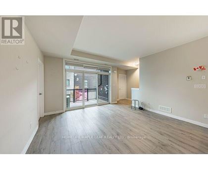 A spacious room with wooden flooring and a sliding glass door leading to a balcony.