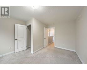 A realtor photo of a bedroom with a white door and carpeted floor.