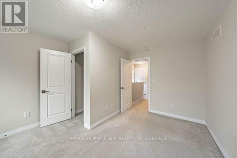 A realtor photo of a bedroom with a white door and carpeted floor.