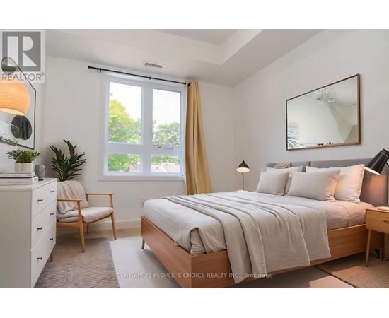 A bedroom with a bed, nightstand, chair, and window.