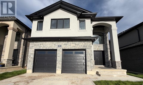 A modern house with a stone facade and two garage doors.
