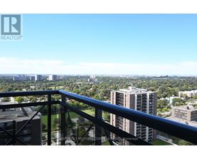 A balcony overlooks a cityscape with buildings and greenery.