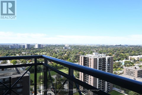 A balcony overlooks a cityscape with buildings and greenery.