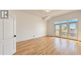 A room with wooden floors and white walls, with a door on the left and a window with blinds on the right.
