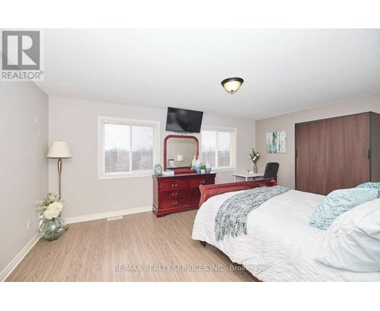 A bedroom with a red dresser and a bed with white bedding.