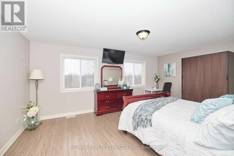 A bedroom with a red dresser and a bed with white bedding.