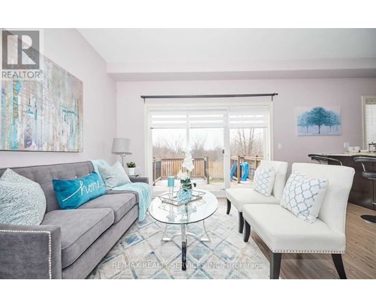 A living room with a grey couch, a glass table, and a painting on the wall.