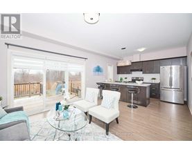 A modern kitchen with a glass table and chairs, and a view of a deck outside the window.