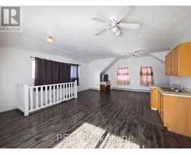 A spacious room with wooden floors and a ceiling fan.