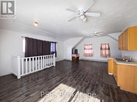 A spacious room with wooden floors and a ceiling fan.