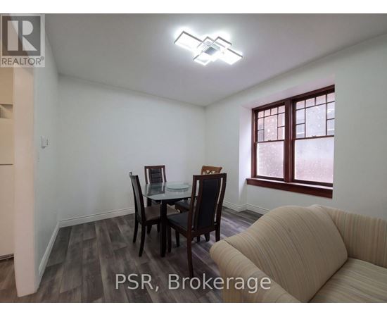A dining room with a table set for two and a sofa.