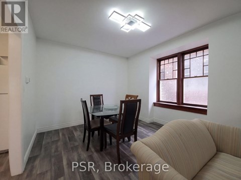 A dining room with a table set for two and a sofa.