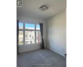 A room with a window and a grey carpet.
