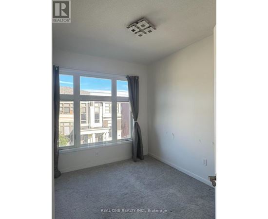 A room with a window and a grey carpet.