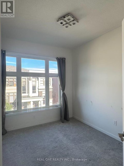 A room with a window and a grey carpet.