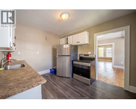 A kitchen with a refrigerator, oven, and sink.