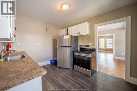 A kitchen with a refrigerator, oven, and sink.