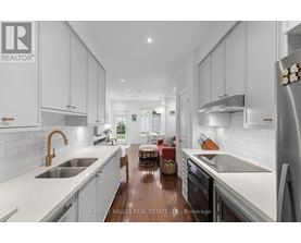 A modern kitchen with white cabinets and a wooden floor.