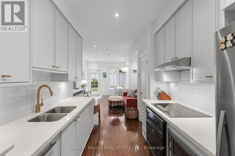 A modern kitchen with white cabinets and a wooden floor.