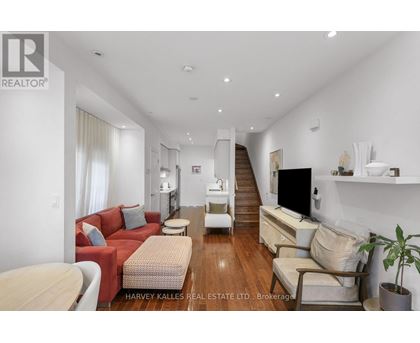 A living room with a red couch and a wooden floor.