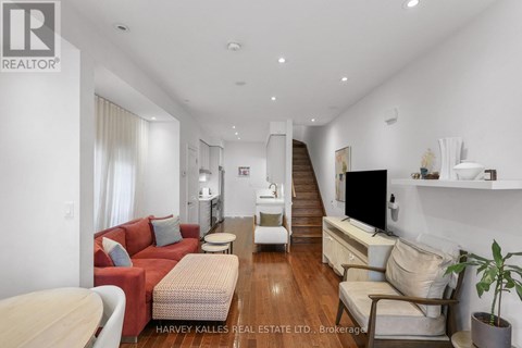 A living room with a red couch and a wooden floor.