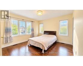 A bedroom with a bed, a window, and a wooden floor.