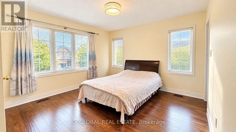 A bedroom with a bed, a window, and a wooden floor.
