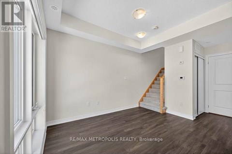A spacious room with a staircase leading to the upper level.