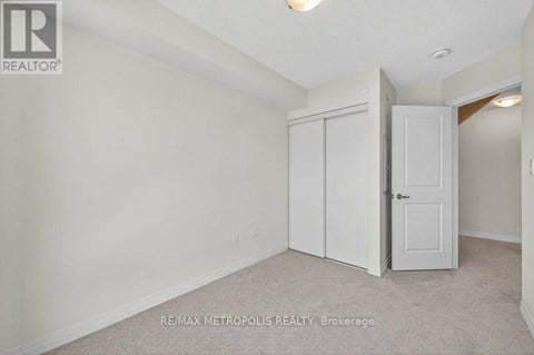 A bedroom with a white door and a white wall.